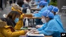 北京一位女子正在医务人员的指导下填写个人信息准备接种新冠病毒疫苗。（2021年1月15日）
