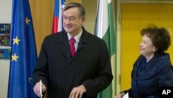 Slovenia's president Danilo Turk, left, casts his ballot as his wife Barbara Miklic, right, looks on at a polling station in Ljubljana, December 4, 2011.