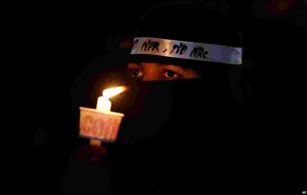 An Indian Muslim woman holds a candle during a protest against a new citizenship law that opponents say threatens India&#39;s secular identity in Bangalore, India.