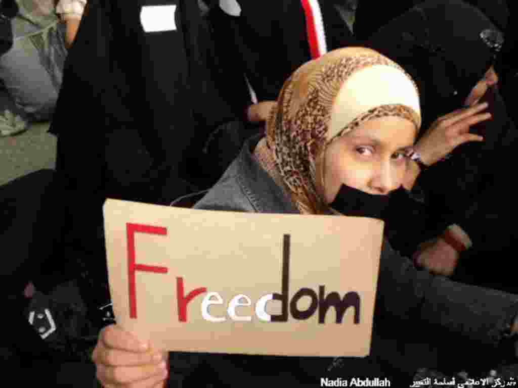 A demonstrator holds up a sign with the word "Freedom" painted in the colors of the Yemen flag. (Photo - Nadia Abdullah)