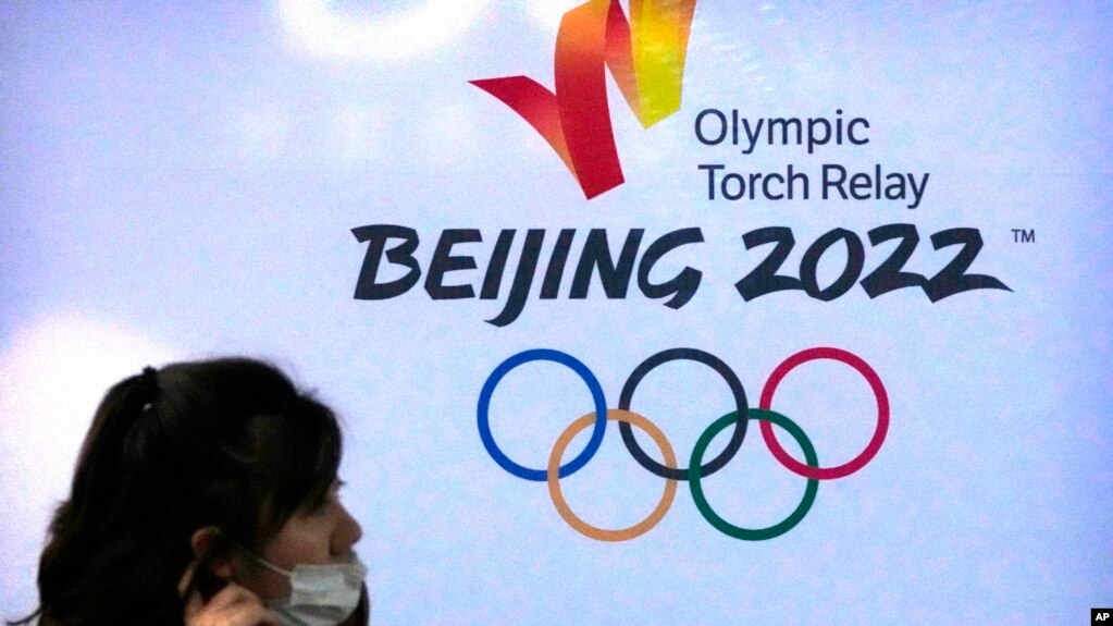 距离北京冬季奥运会仅剩不到三个星期。新冠疫情和人权担忧等诸多因素为本届冬奥平添变数。图为一名戴着口罩的女子走过北京2022冬季奥运会标志。(2021年12月9日美联社资料照)