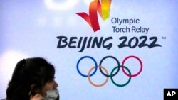 距离北京冬季奥运会仅剩不到三个星期。新冠疫情和人权担忧等诸多因素为本届冬奥平添变数。图为一名戴着口罩的女子走过北京2022冬季奥运会标志。(2021年12月9日美联社资料照)