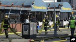 Para petugas pemadam kebakaran membawa selang air di depan sebuah restoran setelah kebakaran terjadi di Fisherman's Wharf di San Francisco, 23 Mei 2020. (Foto: AP)