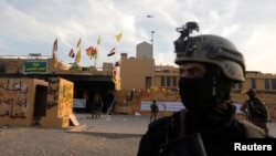 Members of Iraqi security forces are seen in front of U.S. Embassy during a protest to condemn air strikes on bases belonging to Hashd al-Shaabi (paramilitary forces), in Baghdad, Iraq January 1,…