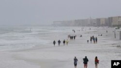 Para pengunjung berjalan di pantai saat badai sub-tropis melanda, Senin, 28 Mei 2018, di Pulau Okaloosa, Florida.