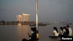 FILE - People uses their mobile phones on the Tonle Sap riverside in Phnom Penh, Cambodia, Feb. 18, 2021.