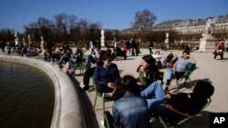 People sunbathe at the Tuileries garden in Paris, as temperatures hit 19 degrees Celsius (62 Fahrenheit), Feb. 24, 2021. France is considering new local restrictions to deal with a worsening COVID-19 situation. 