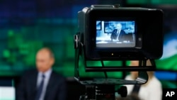 FILE - Russian President Vladimir Putin is shown on the screen of a camera viewfinder at the headquarters of "Russia Today" television channel in Moscow, Russia, June 11, 2013. Ukraine's state security agency raided offices of the RIA Novosti news agency and RT television Tuesday in Kyiv.