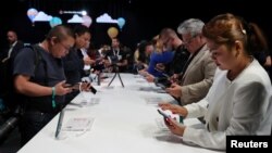 FILE - People look at display models of the Huawei Mate20 smartphone series at a launch event in London, Britain, Oct. 16, 2018. 