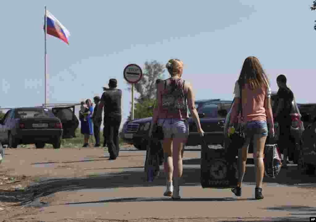 People carry their belongings as they walk to cross the border into Russia at the Ukrainian-Russian border checkpoint in Severniy, Luhansk region, eastern Ukraine, July 2, 2014.