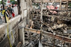 FILE - Onlookers inspect the burnt ruins of the Minnehaha Liquor store near the Minneapolis 3rd Police Precinct, in Minneapolis, Minnesota, June 2, 2020.