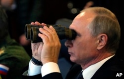 FILE - Russian President Vladimir Putin watches a military exercise at a training ground at the Luzhsky Range, near St. Petersburg, Sept. 18, 2017. Russia flexing its military muscle has triggered worries among its nearest NATO neighbors - Estonia, Latvia and Lithuania - especially after Moscow's 2014 annexation of Ukraine's Crimea.