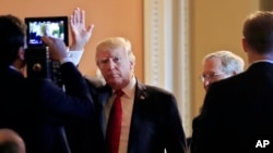 President Donald Trump, followed by Senate Majority Leader Mitch McConnell., waves as he arrives for a lunch with Republican senators at the Capitol in Washington, Oct. 24, 2017.