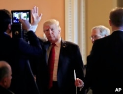 President Donald Trump, followed by Senate Majority Leader Mitch McConnell., waves as he arrives for a lunch with Republican senators at the Capitol in Washington, Oct. 24, 2017.
