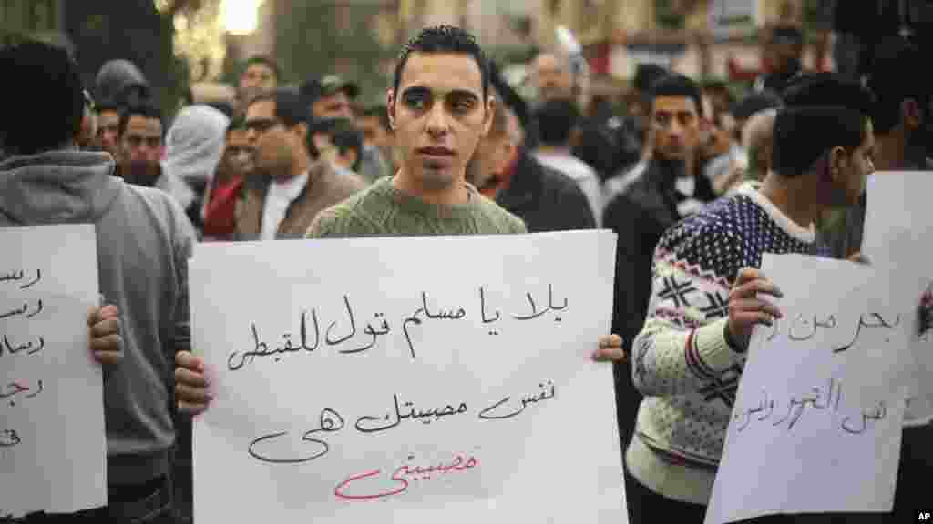 An Egyptian man holds a poster with Arabic that reads "Muslims and Copts are in the same tragedy" during a protest against the slaying of Egyptian Coptic Christians in Libya by militants associated with the Islamic State group, in Cairo, Egypt, Feb. 16, 2