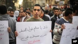 An Egyptian man holds a poster that reads "Muslims and Copts are in the same tragedy" in Arabic, protesting the slaying of Egyptian Coptic Christians in Libya by militants associated with the Islamic State group, in Cairo, Egypt, Feb. 16, 2015.