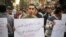 FILE - An Egyptian man in Cairo holds a poster with Arabic that reads "Muslims and Copts are in the same tragedy" during a protest against the slaying of Egyptian Coptic Christians in Libya by militants associated with the Islamic State group.