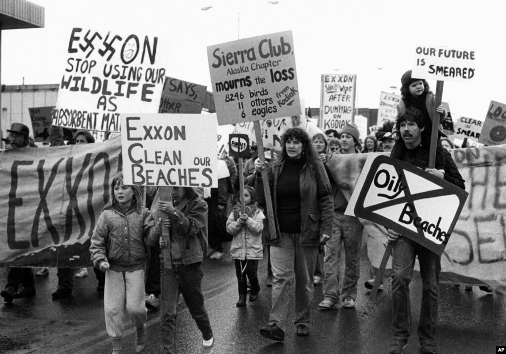 FILE - People in Kodiak carry signs to protest the Exxon oil spill in Anchorage, Alaska, May 27, 1989. 