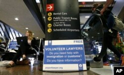 Asti Gallina (left) a volunteer law student from the University of Washington, sits at a station near where passengers arrive on international flights at Seattle-Tacoma International Airport, Feb. 28, 2017, in Seattle.