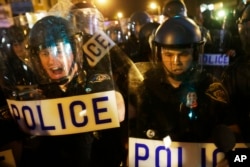 Police in riot gear push back on media and a crowd gathering in the street after a 10 p.m. curfew went into effect Thursday, April 30, 2015.