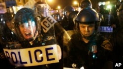 Polisi mendorong media dan kerumunan di jalan setelah jam malam berlaku di Baltimore (30/4). (AP/David Goldman)