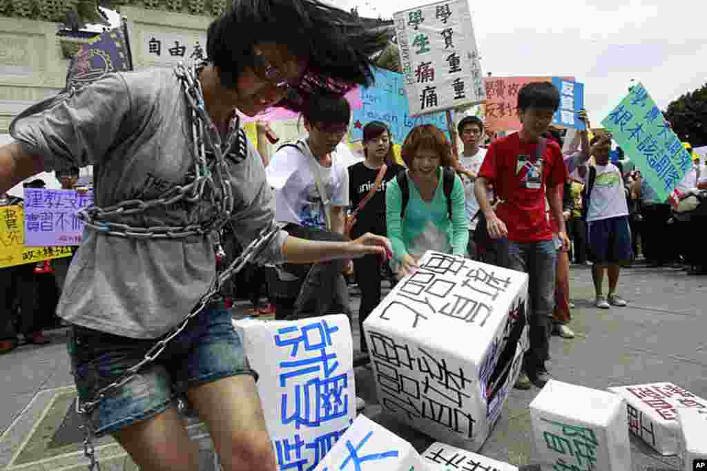 Students enact a skit demanding a freeze in tuition increases along side thousands of anti-government protesters demanding higher wages and better treatment during a May Day march in downtown Taipei, Taiwan, May 1, 2012. (AP Photo)