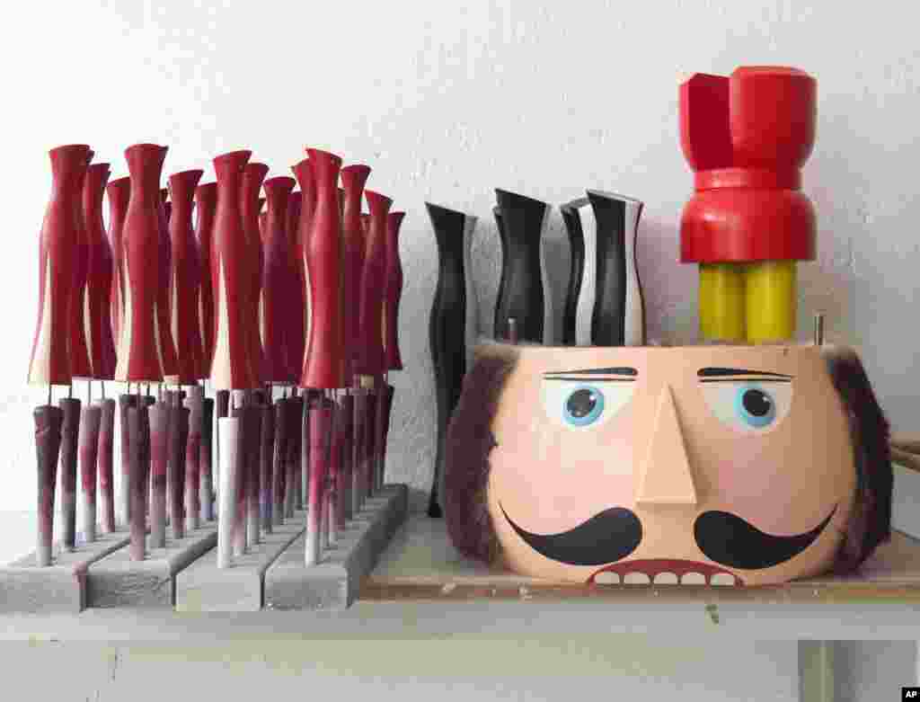 A part of a traditional wooden Christmas nutcracker figure and other wooden parts stand on a table in one of the factory rooms in the Erzgebirgische Holzkunst Gahlenz company in Gahlenz, southeastern Germany. The traditional wooden Christmas figures aresold all over the world.