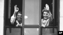 In this 1985 file photo, President Ronald Reagan gives the A OK sign from the window of his hospital room at the Naval Medical Center in Bethesda, Maryland as first lady Nancy Reagan waves to a small group below. The president is recovering from surgery performed Saturday to remove a cancerous polyp. (AP Photo/Scott Stewart)