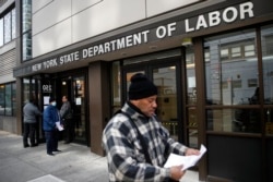 Visitors to the Department of Labor are turned away at the door by personnel due to closures over coronavirus concerns, Wednesday, March 18, 2020, in New York. Applications for jobless benefits are surging in some states