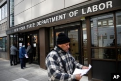 Visitors to the Department of Labor are turned away at the door by personnel due to closures over coronavirus concerns, Wednesday, March 18, 2020, in New York. Applications for jobless benefits are surging in some states
