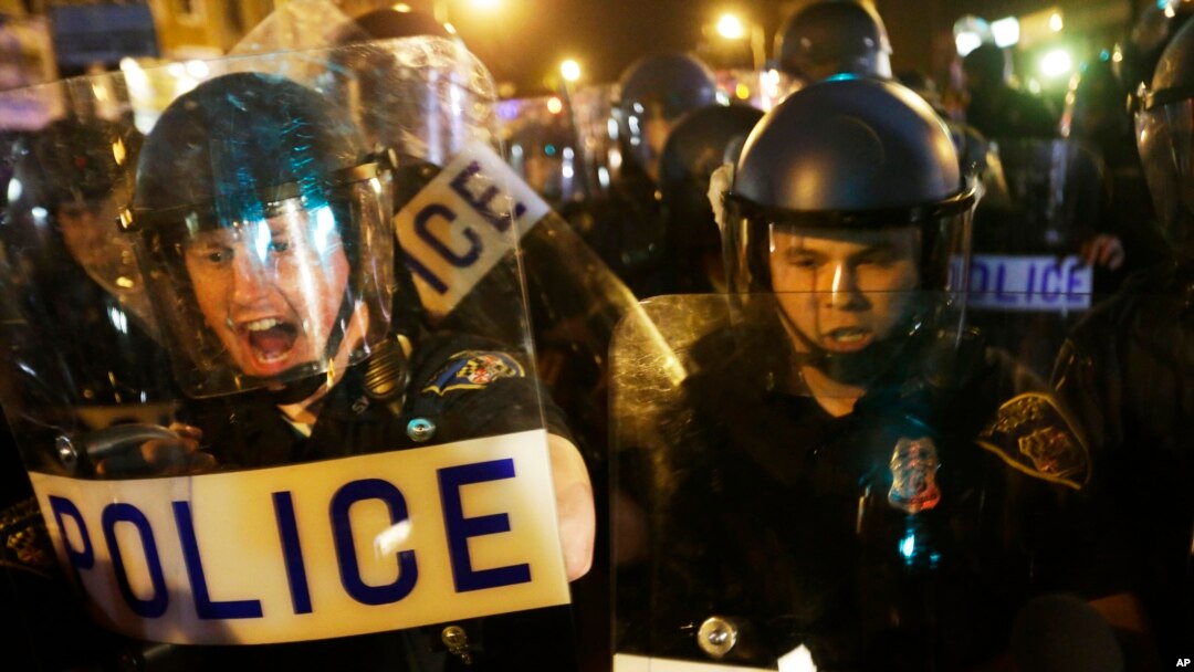 Polisi mendorong media dan kerumunan di jalan setelah jam malam berlaku di Baltimore (30/4). (AP/David Goldman)