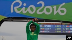 Silver medal Ethiopia's Feyisa Lilesa crosses his arms as he celebrates on the podium after the men's marathon at the 2016 Summer Olympics in Rio de Janeiro, Brazil, Aug. 21, 2016. 