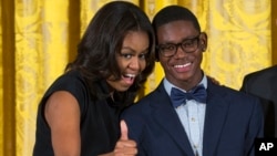 First lady Michelle Obama, pictured with Andre Massey of Deep Center Inc., Savannah, Ga., gives a sign of approval to the youth's father in the audience during the 2015 National Arts and Humanities Youth Program Awards at the White House, Nov. 17, 2015.