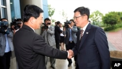 Suh Ho, kepala delegasi tingkat pekerja Korea Utara (kanan) berjabat tangan dengan pejabat setingkat dari Korea Utara, Park Chol Su, setibanya di lokasi rapat Komite Manajemen di Kawasan Industri Kaesong, Korea Utara (10/7). 
