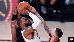 Los Angeles Lakers' LeBron James, left, shoots over Houston Rockets' Austin Rivers during the second half of an NBA conference semifinal playoff basketball game, Sept. 12, 2020, in Lake Buena Vista, Fla. 