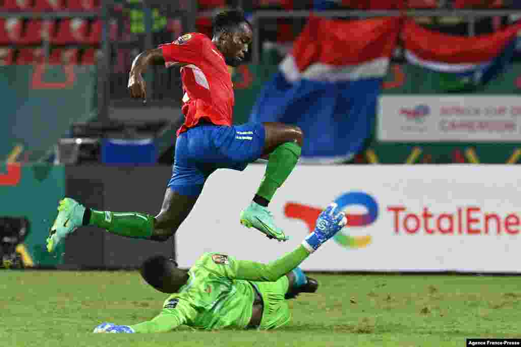 Gambia&#39;s forward Dembo Darbou (up) jumps to avoid Mauritania&#39;s goalkeeper Babacar Diop during the Group F football match between the two countries.