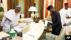 In this photo released by the Nigeria State House, Nigeria's President Muhammadu Buhari, left, and Vice President Yemi Osinbajo, right, smile before a meeting at the presidential palace in Abuja, Nigeria, Monday, March 13, 2017. (Sunday Aghaeze/Nigeria State House via AP)