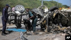 Somali soldiers check the wreckage of a car bomb outside the UN's office in Mogadishu, Somalia on July 26, 2016. 