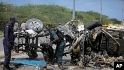 wanajeshi wa Somalia wakiangalia mabaki ya gari lililotegwa bomu mjini Mogadishu.