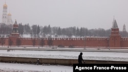 FILE - A pedestrian walks along an embankment of the Moskva river with the Kremlin on the background during a snowfall in Moscow, Jan. 21, 2022. 