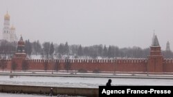 Un peatón camina a lo largo de un terraplén del río Moskva con el Kremlin al fondo durante una nevada en Moscú el 21 de enero de 2022. AFP