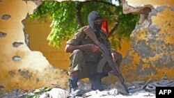 FILE - A Somali soldier stands guard next to the site where al-Shabab militants carried out a suicide attack against a military intelligence base in Mogadishu, June 2015.