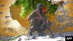 FILE - A Somali soldier stands guard next to the site where al-Shabab militants carried out a suicide attack against a military intelligence base in Mogadishu, June 21, 2015.