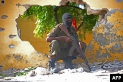 FILE - A Somali soldier stands guard next to the site where al-Shabab militants carried out a suicide attack against a military intelligence base in Mogadishu, June 21, 2015.