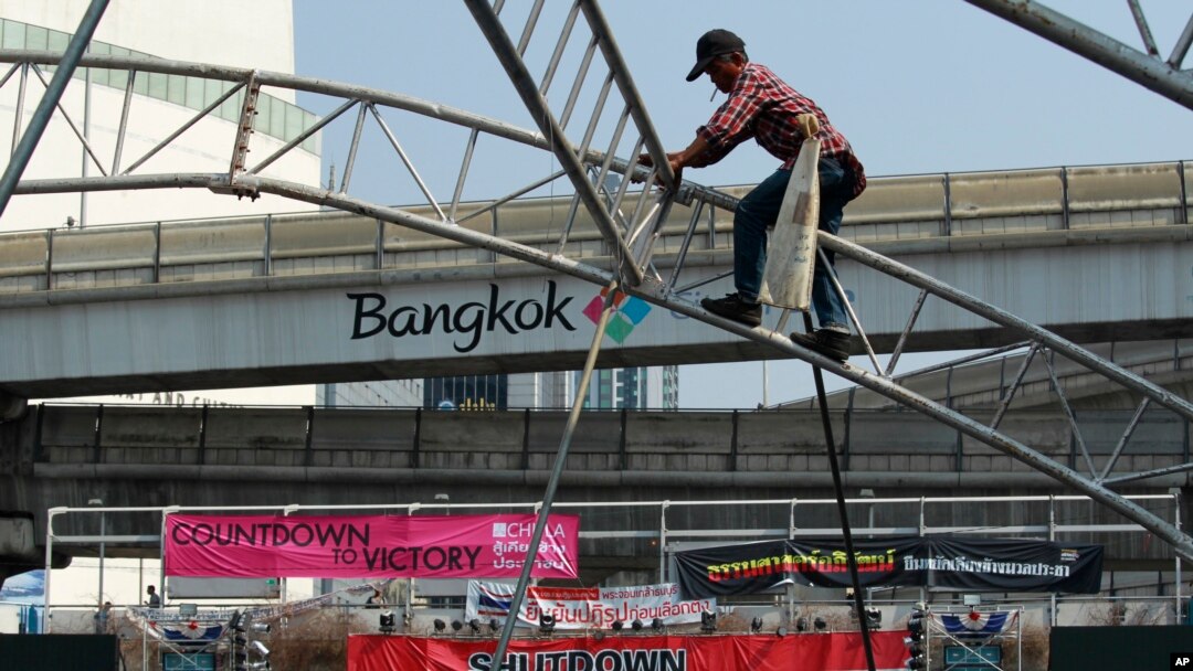 Seorang pekerja konstruksi membongkar tenda di panggung utama yang digunakan untuk aksi protes di jalan utama Bangkok, Thailand.