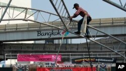 Seorang pekerja konstruksi membongkar tenda di panggung utama yang digunakan untuk aksi protes di jalan utama Bangkok, Thailand.