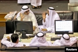 FILE - Investors watch a monitor at the Dubai Financial Market.