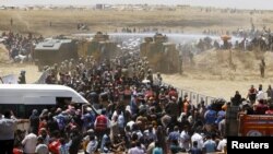 Turkish military use water cannon to stop Syrian refugees as they wait behind the border fences to cross into Turkey, near Akcakale in Sanliurfa province, Turkey, June 10, 2015. REUTERS/Osman Orsal TPX IMAGES OF THE DAY - RTX1FX37