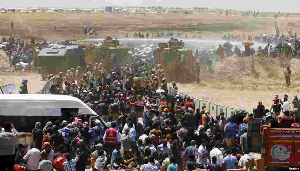 The Turkish military uses water cannons to stop Syrian refugees as they wait behind the border fences to cross into Turkey, near Akcakale in Sanliurfa province.