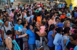 FILE - Migrants, many who were returned to Mexico under the Trump administration’s “Remain in Mexico” program, wait in line to get a meal in an encampment near the Gateway International Bridge in Matamoros, Mexico, Aug. 30, 2019,